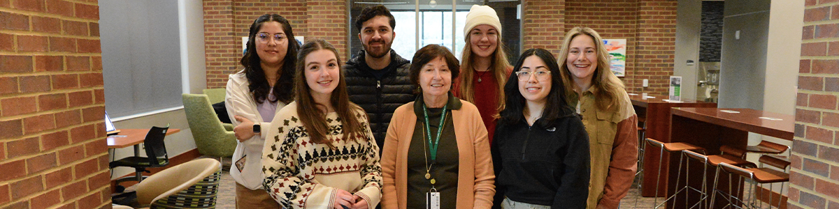 A group of seven individuals posing with Dr. Smith together in a modern space with brick walls. 
