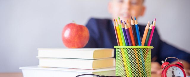 apple on pile of school books with student in background