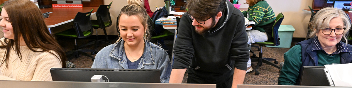 Four students are seated at a computer station.