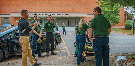 A group of EMT's carrying a stretcher towards a building