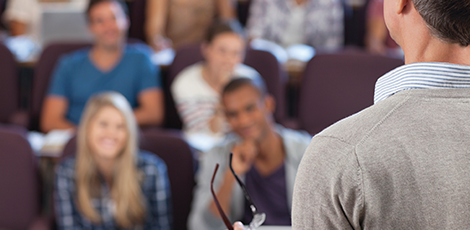 A man teaching english to a group of students sitting in a theater