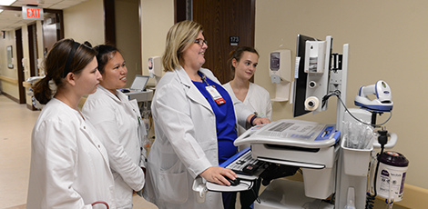 A group of four nurses examining a medical computer