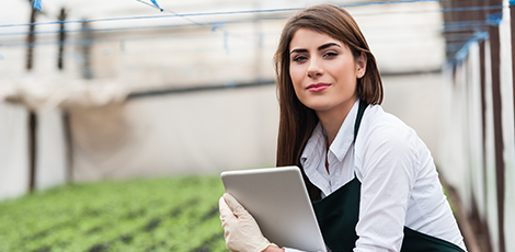 A woman holding an electronic tablet while standing in front of an indoor farm