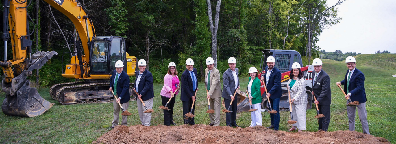 People with shovels dig in dirt 