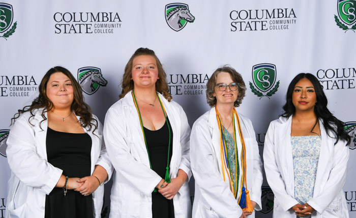 Four people pose in front of a white background.