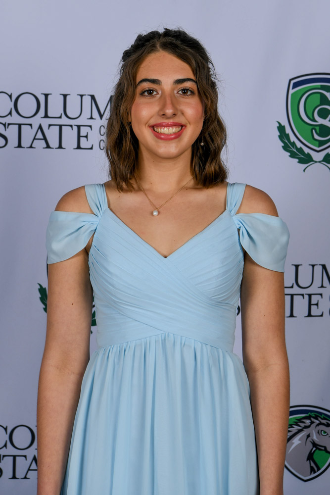 A woman stands in front of a white background.