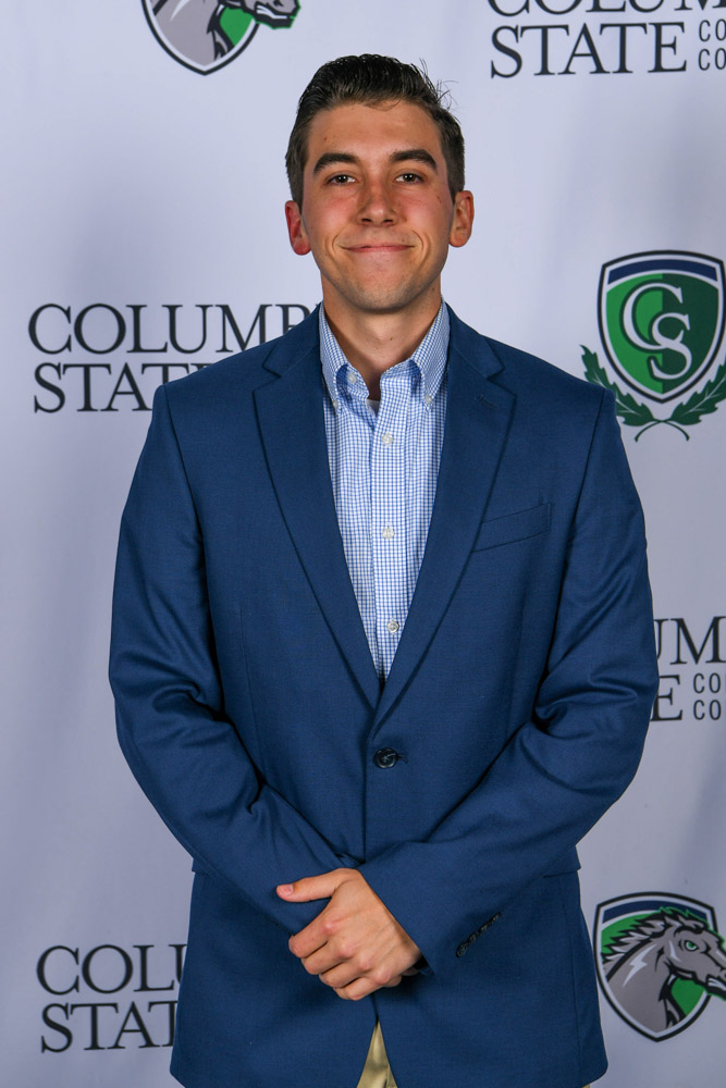 A man stands in front of a white background. 