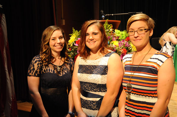 group of three ladies in front of flowers