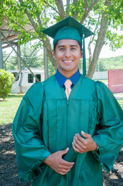 guy in cap and gown in front of tree